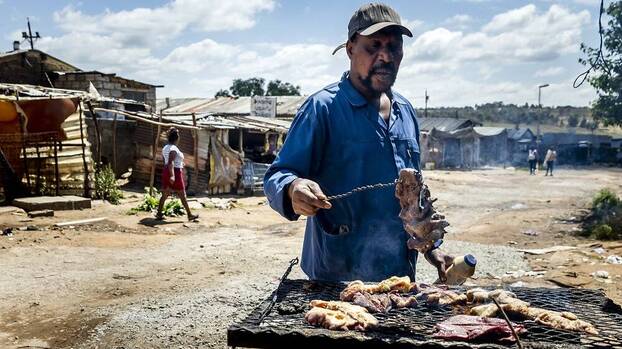 Ein Mann grillt auf der Straße in der Township Soweto, Südafrika, 17.10.2023.