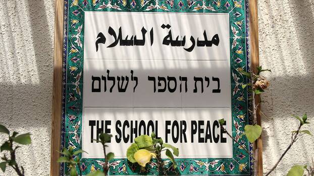 An einer Wand der Schule in dem Dorf Newe Schalom/Wahat al-Salam in Israel hängt ein auf Arabisch, Hebräisch und Englisch beschriftetes Schild mit der Aufschrift «The School of Peace». In dem Ort leben zu gleichen Teilen Israelis und Palästinenser friedlich zusammen.