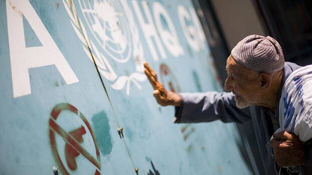 An elderly person seen banging on the gate at the UNRWA office in Gaza City, 2018.